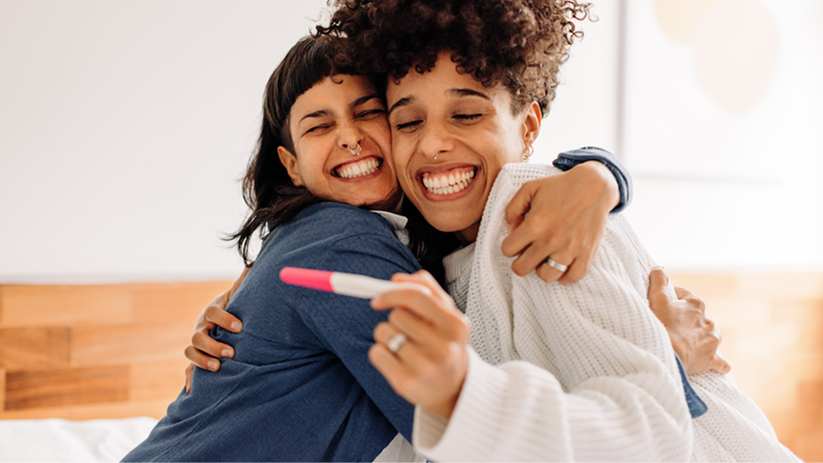 Two people looking at a pregnancy test with big smiles